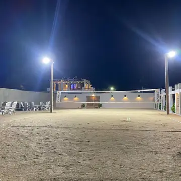 La cancha de beach tennis de noche con las luces encendidas.