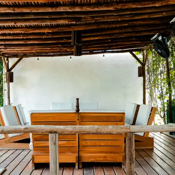 Deck de madera con sofás bajo el techo de caña.