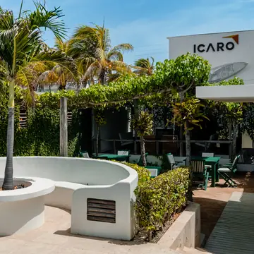 El jardín de la posada con el letrero de Ícaro y las palmeras.