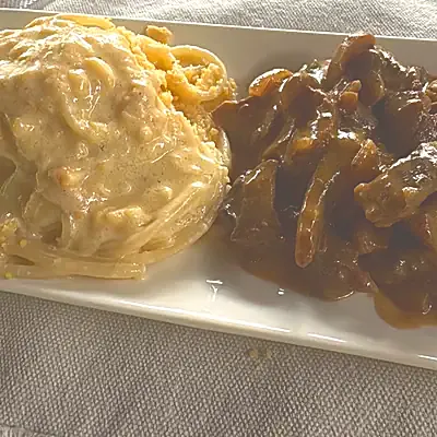 Pasta en salsa blanca con carne en salsa.