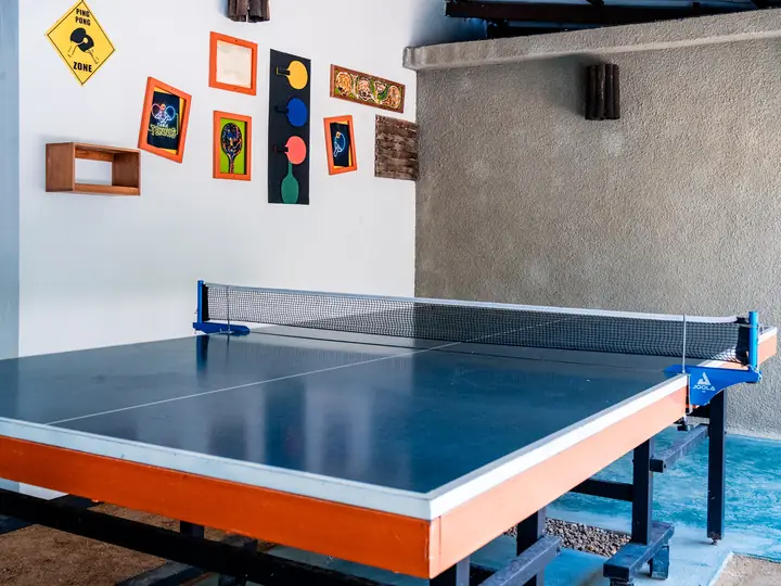 Mesa de ping pong de la posada, con cuadros en la pared.