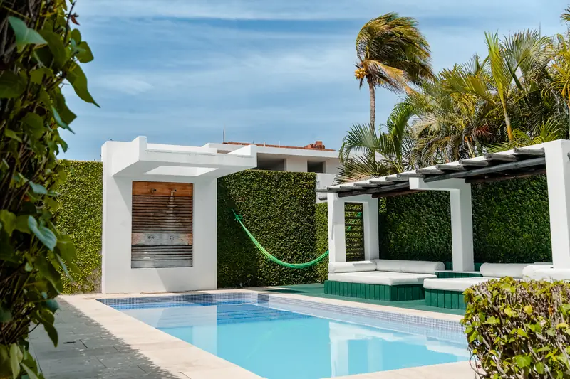 La piscina de la posada con la hamaca y las palmeras.