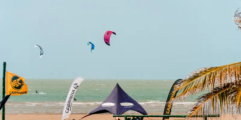 La playa de Adícora con kites en el cielo y la carpa de la escuela en la arena.
